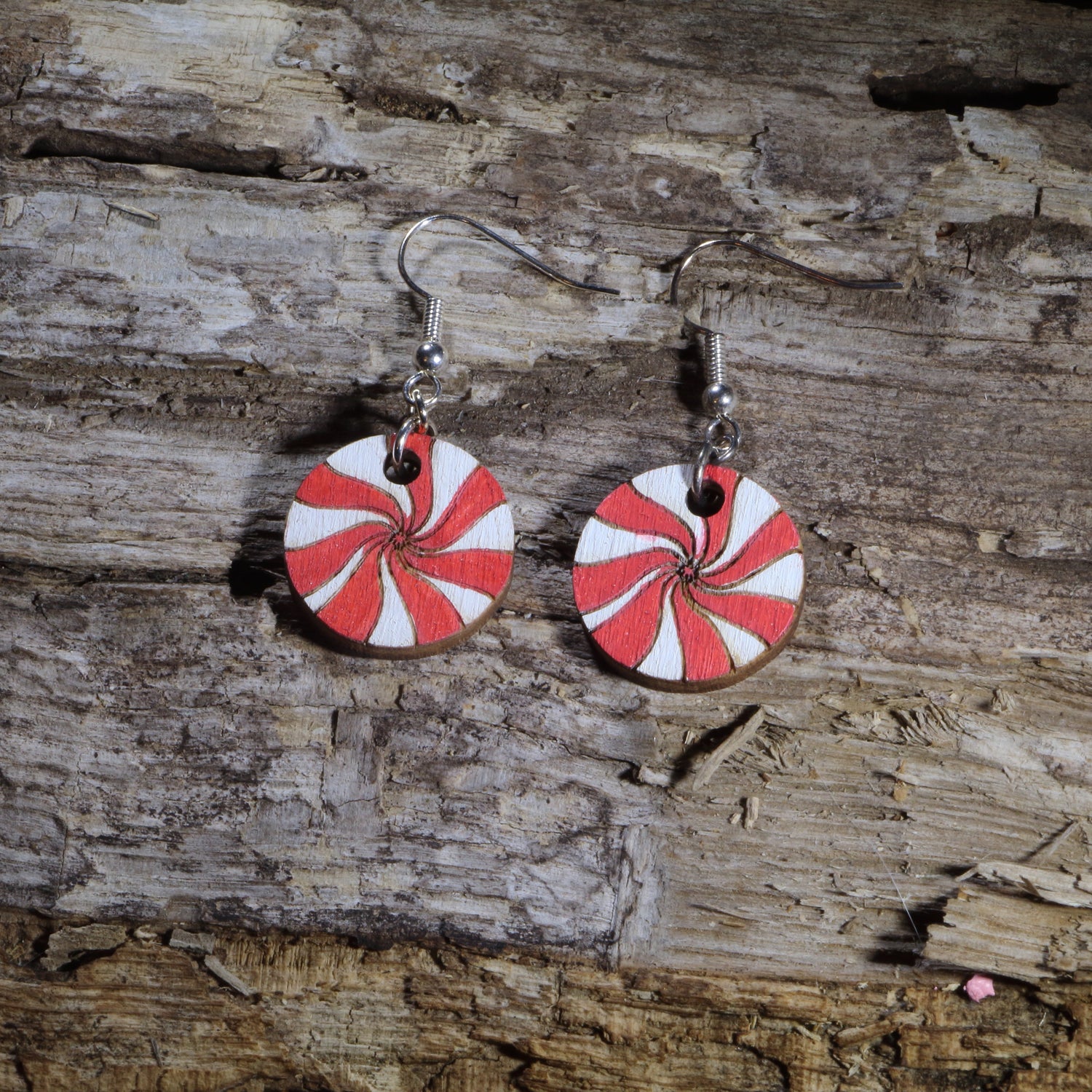 Hand-painted wooden peppermint candy dangle earrings featuring classic red and white swirled peppermint mints. Crafted from lightweight wood with hypoallergenic .925 sterling silver hooks, these festive holiday earrings are perfect for Christmas celebrations, winter parties, candy lovers, cookie exchanges, stocking stuffers, peppermint-themed outfits, and anyone who loves sweet holiday-inspired jewelry.