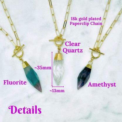 Three gold-plated paperclip chain necklaces with crystal pendants are displayed on a white marble background with pink text labels reading &