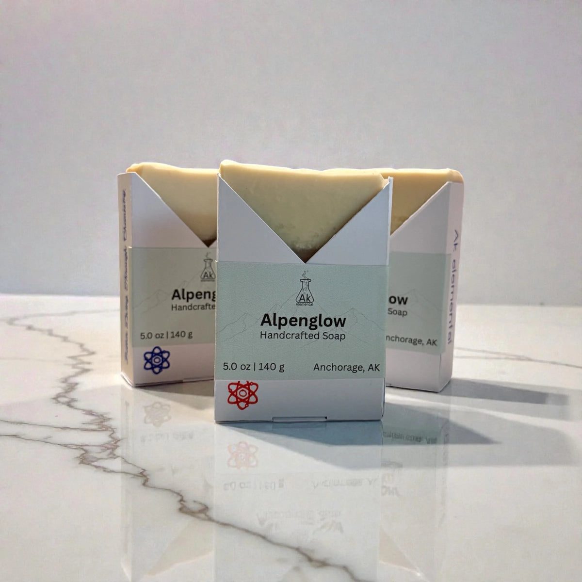 Three Alpenglow soaps sitting on a marble counter.