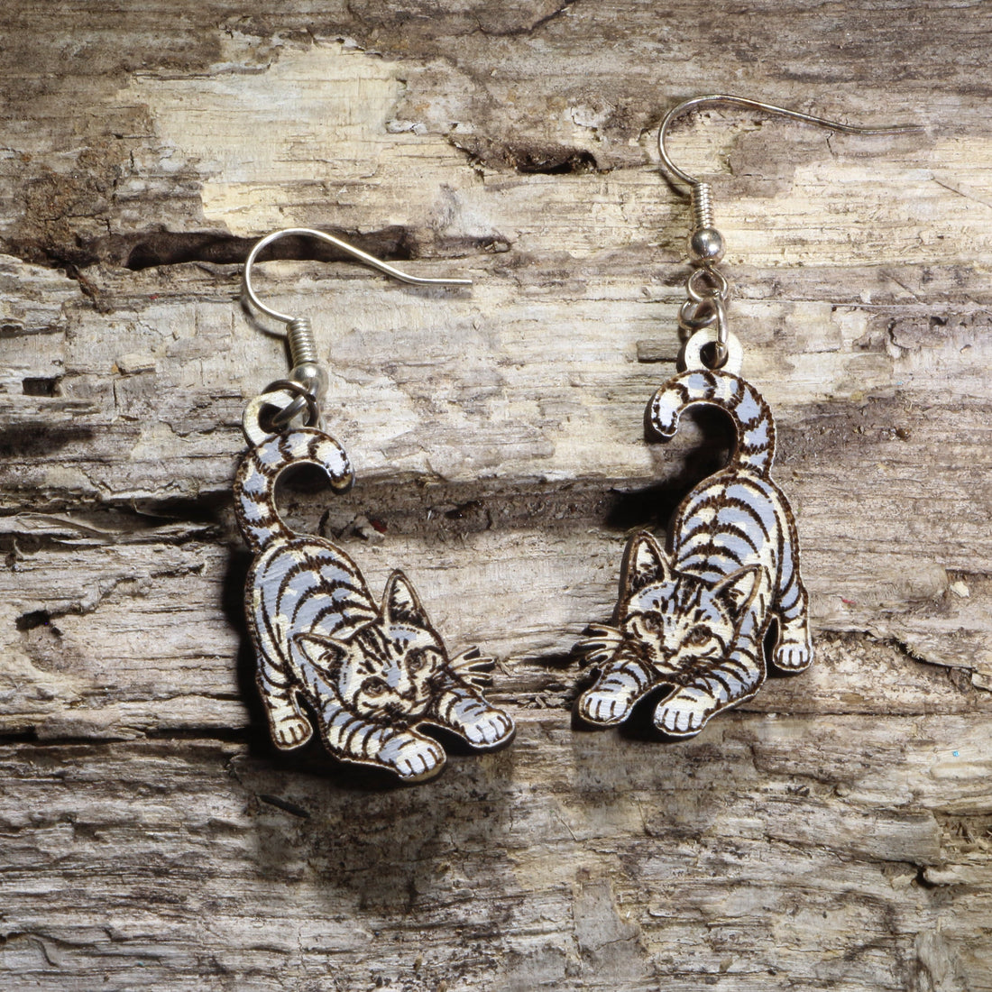 Handcrafted playful gray tabby cat wooden dangle earrings featuring an adorable gray tabby with bright green eyes and a playful pose. Lightweight laser-cut wooden earrings with hypoallergenic .925 sterling silver hooks, perfect for cat lovers, tabby cat owners, pet parents, feline enthusiasts, and unique handmade animal jewelry.