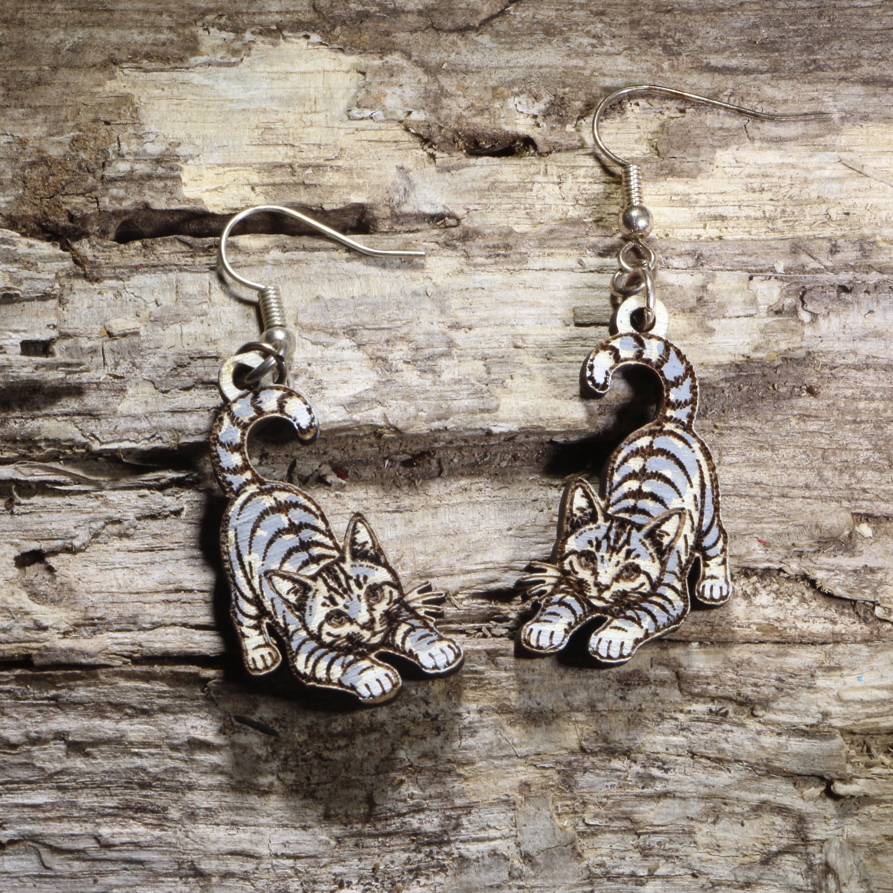 Handcrafted playful gray tabby cat wooden dangle earrings featuring an adorable gray tabby with bright green eyes and a playful pose. Lightweight laser-cut wooden earrings with hypoallergenic .925 sterling silver hooks, perfect for cat lovers, tabby cat owners, pet parents, feline enthusiasts, and unique handmade animal jewelry.