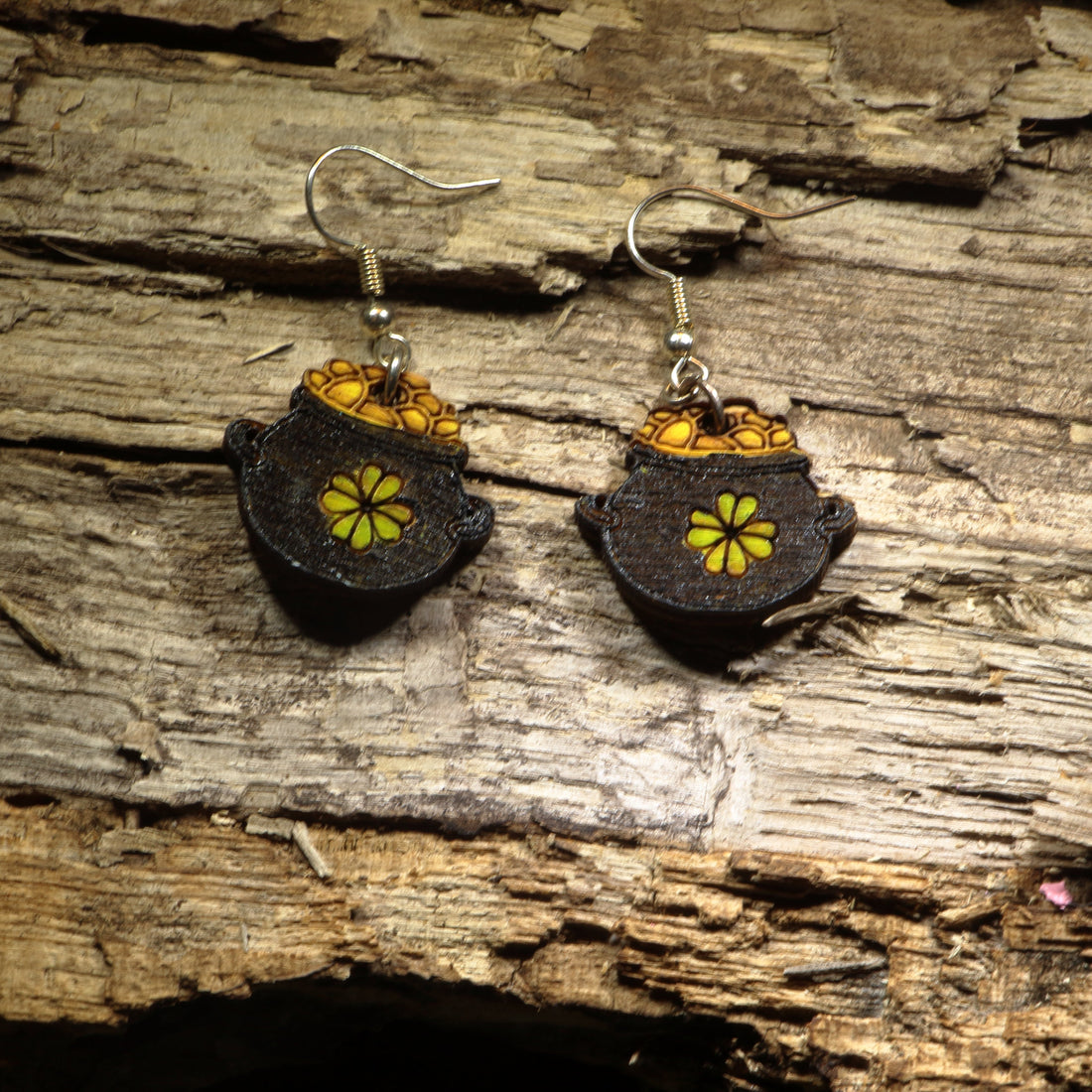 Hand-painted wooden pot of gold dangle earrings featuring a treasure-filled pot overflowing with bright gold coins inspired by Irish folklore. Crafted from lightweight wood with hypoallergenic .925 sterling silver hooks, these festive earrings are perfect for St. Patrick&