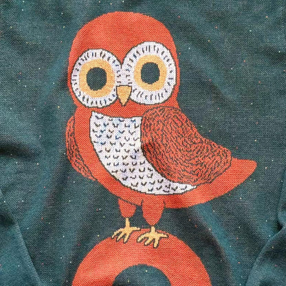 Detail of the knitted owl design on the forest green Owl on a Vowel graphic knit sweater by Jedd