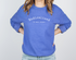 Person wearing a blue sweatshirt with white typewriter like text reading radicalized by basic decency on a plain background
