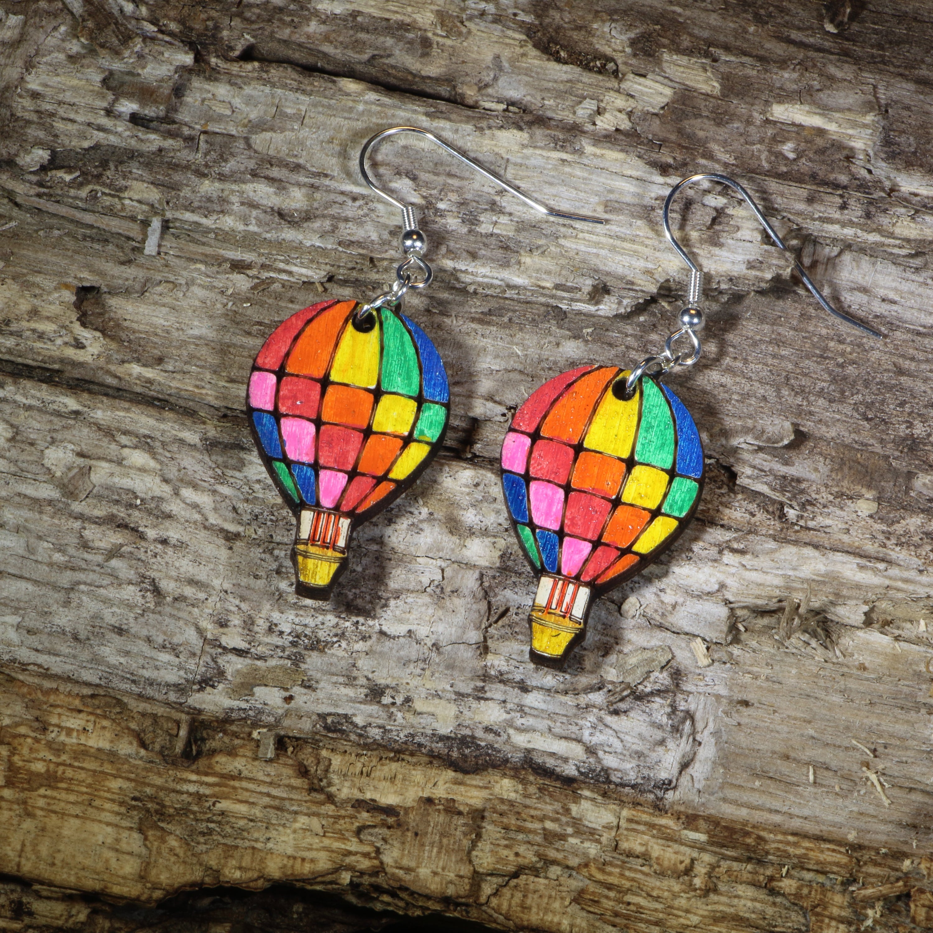 Hand-painted wooden rainbow hot air balloon dangle earrings featuring colorful stained-glass inspired balloon panels, hypoallergenic sterling silver hooks, and lightweight travel jewelry for adventure lovers, festival outfits, and rainbow accessory fans by Cate&