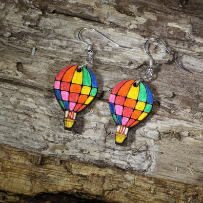 Hand-painted wooden rainbow hot air balloon dangle earrings featuring colorful stained-glass inspired balloon panels, hypoallergenic sterling silver hooks, and lightweight travel jewelry for adventure lovers, festival outfits, and rainbow accessory fans by Cate&