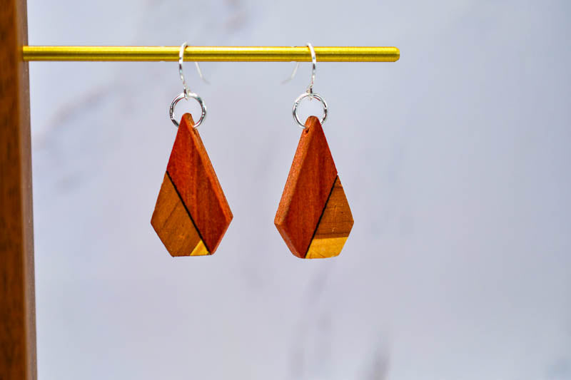 Two-tone wooden cone earrings shown in detail, hand-finished hardwood with visible grain contrast