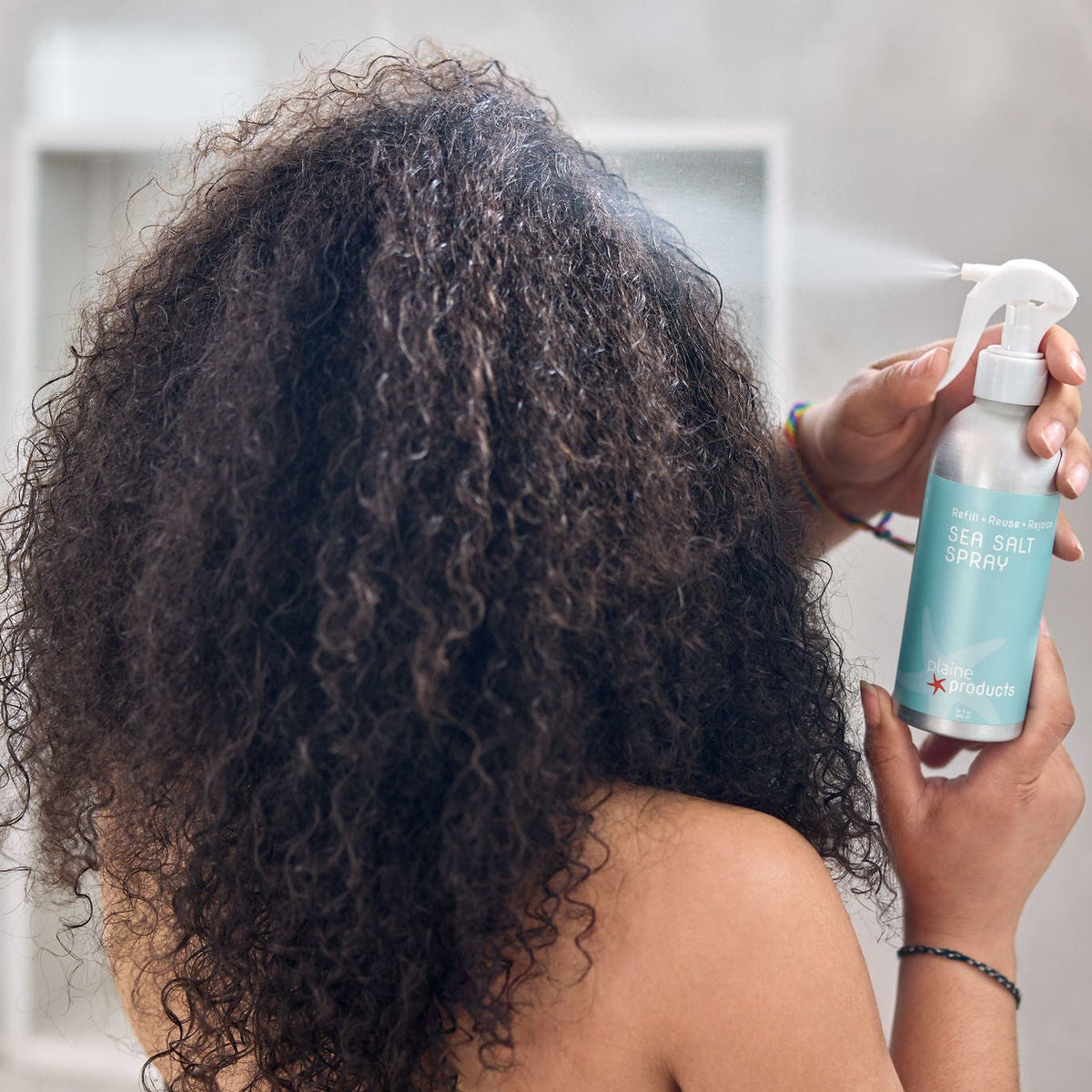 Women spraying eco friendly sea salt spray on 4c curls