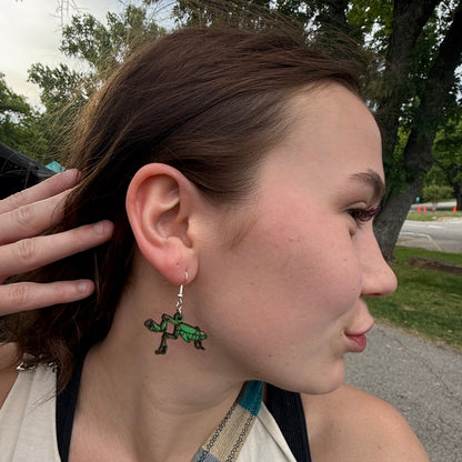 Side profile of a customer wearing hand-painted green praying mantis wooden dangle earrings. This image demonstrates the scale, movement, and eye-catching detail of these lightweight handmade earrings with hypoallergenic .925 sterling silver hooks. Ideal for insect lovers, outdoor adventurers, gardeners, and anyone looking for fun, nature-inspired wearable art.