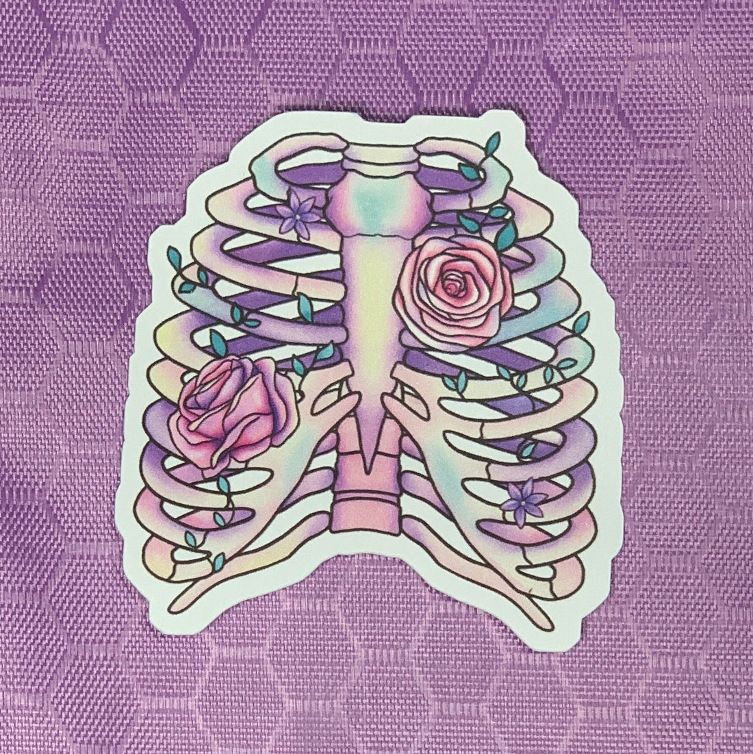 Our dreamy and whimsical die cut skeletal remains sticker features a softly pastel shaded ribcage with vined pink roses winding around the bones.&amp;nbsp;