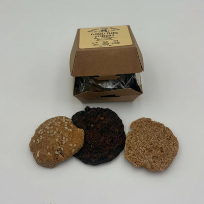 Three textured bath stones in brown, black, and tan are displayed in front of their open kraft paper packaging box on a light gray background.