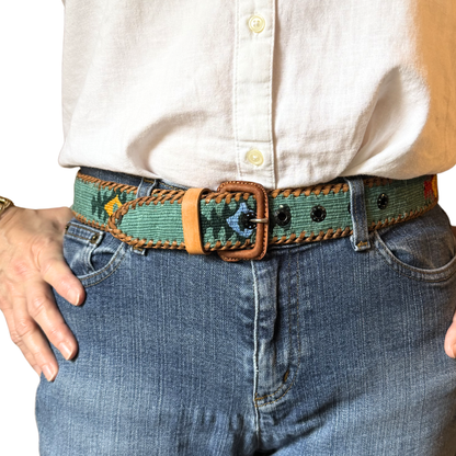 Person wearing a colorful belt with a white shirt and blue jeans.