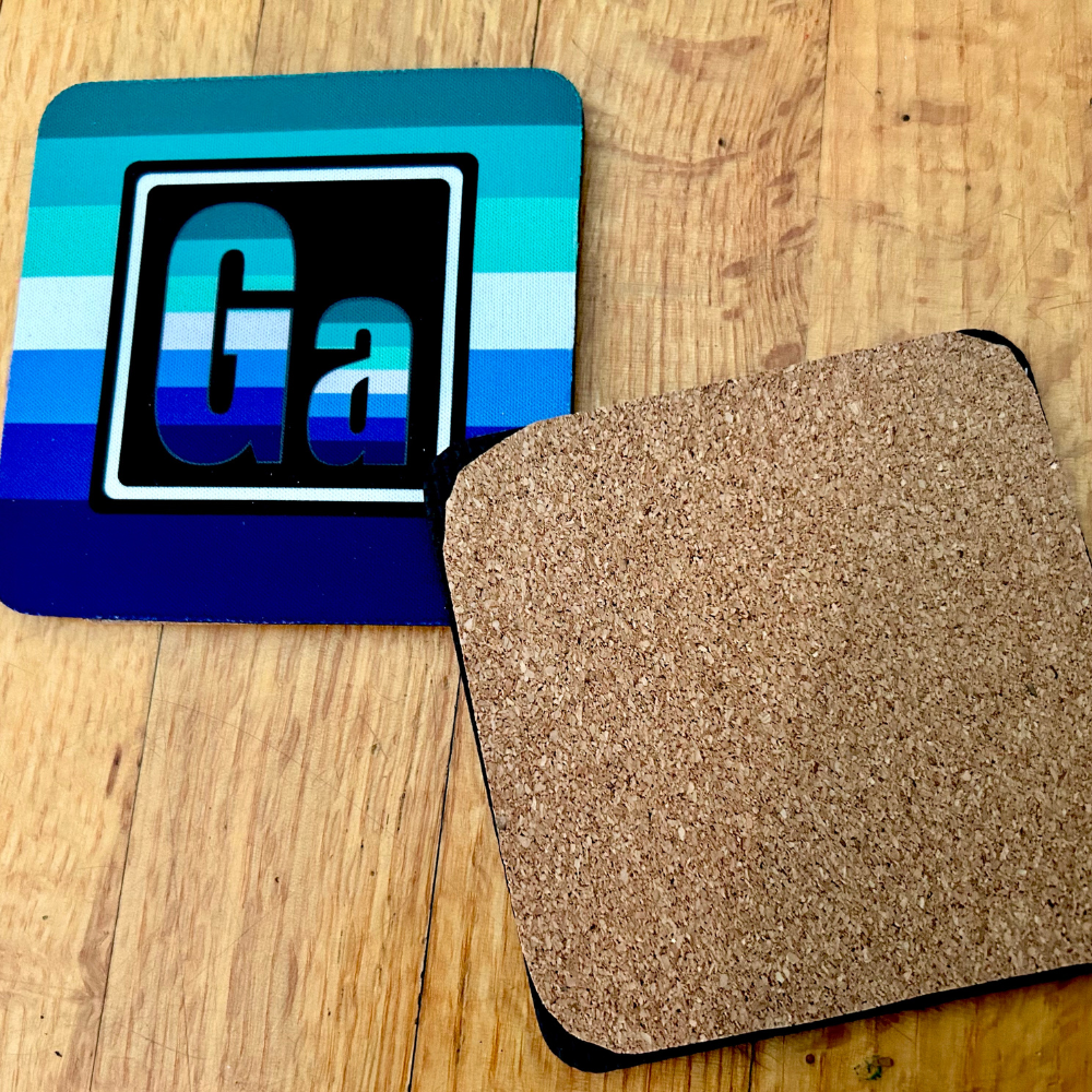 The Gay Element coaster. On the left is the front of the Gay element with the colors of the Gay flag. On the right is te back of our coasters, which have cork across the back of the coaster. 
