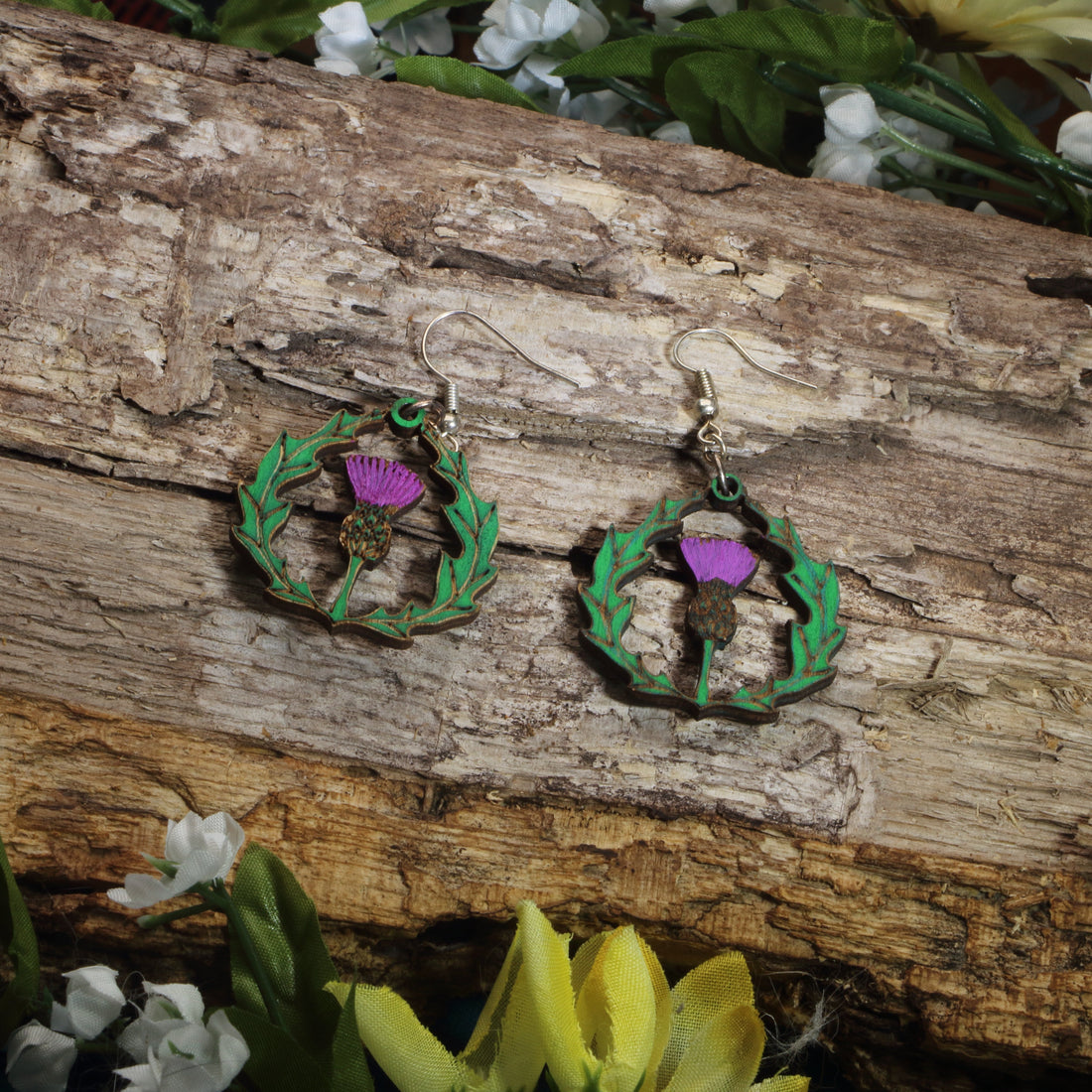 Hand-painted wooden thistle dangle earrings featuring a purple Scottish thistle framed by Celtic-inspired greenery, hypoallergenic sterling silver hooks, and lightweight heritage jewelry for Scottish pride, Celtic culture, and nature lovers by Cate’s Concepts