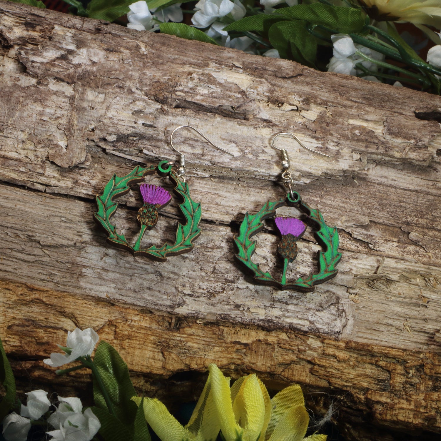 Hand-painted wooden thistle dangle earrings featuring a purple Scottish thistle framed by Celtic-inspired greenery, hypoallergenic sterling silver hooks, and lightweight heritage jewelry for Scottish pride, Celtic culture, and nature lovers by Cate’s Concepts