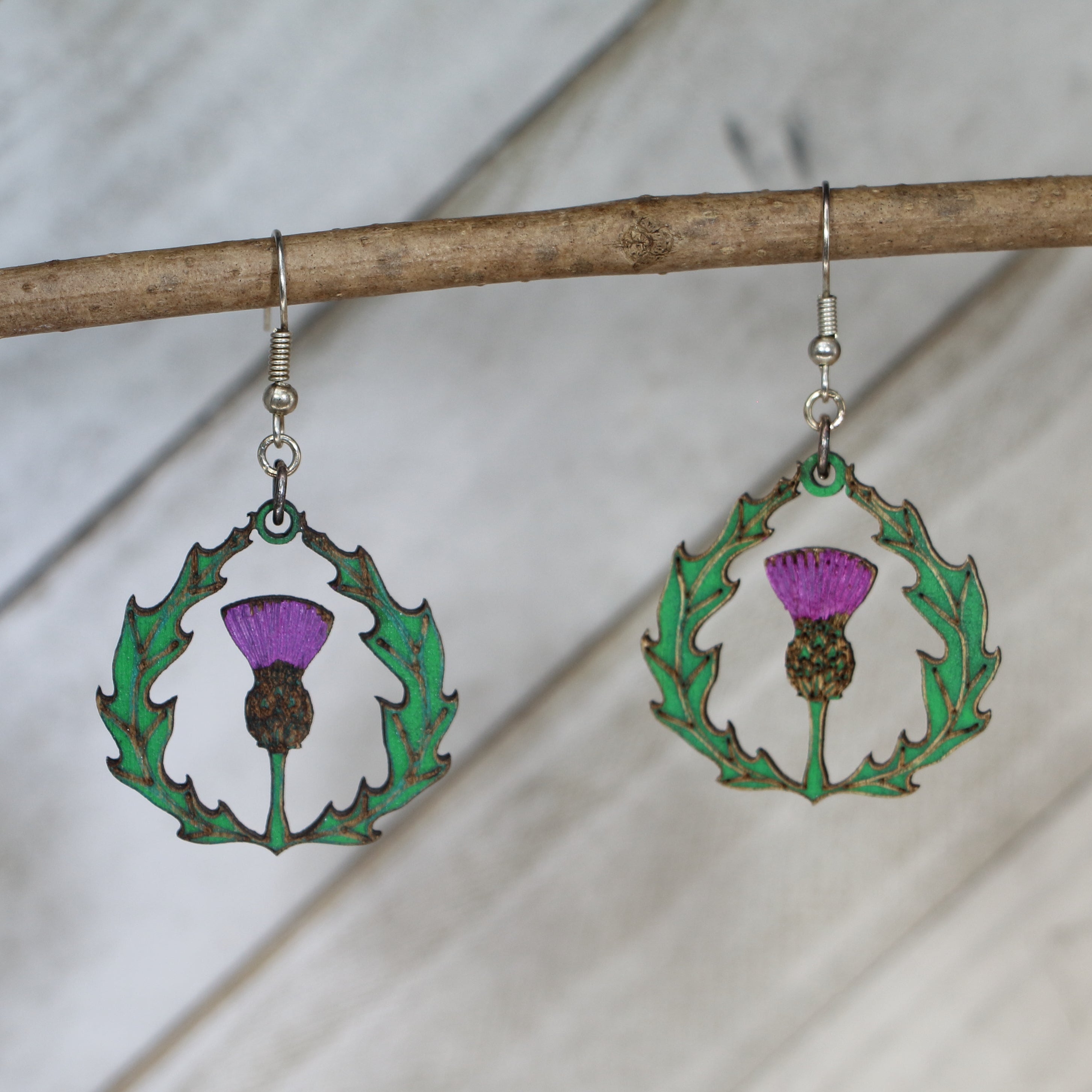 Hand-painted wooden thistle dangle earrings with Celtic Scottish flower design and hypoallergenic sterling silver hooks, lightweight botanical jewelry for heritage lovers and nature-inspired style by Cate’s Concepts
