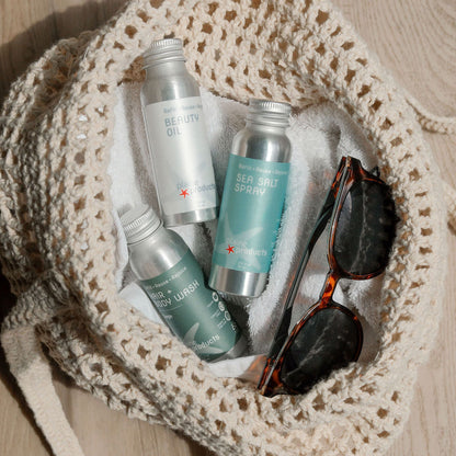 Crocheted bag with travel sea salt spray, hair + Body wash 2 in one, and beauty oil to take care of hair and skin along with sunglasses.