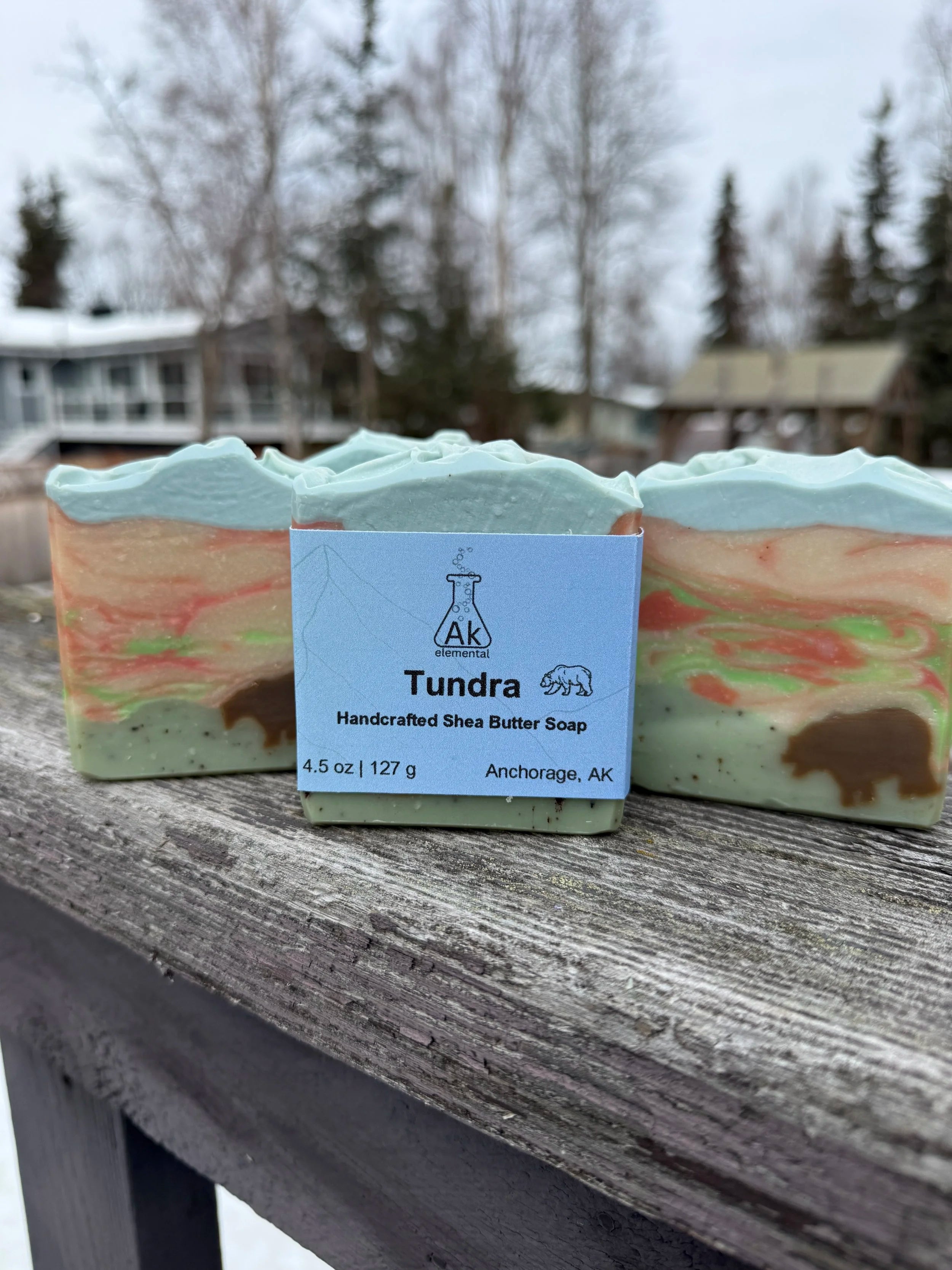Rectangular soap bar with avocado oil, coconut milk, and bear embed, styled outdoors in snowy Alaska setting