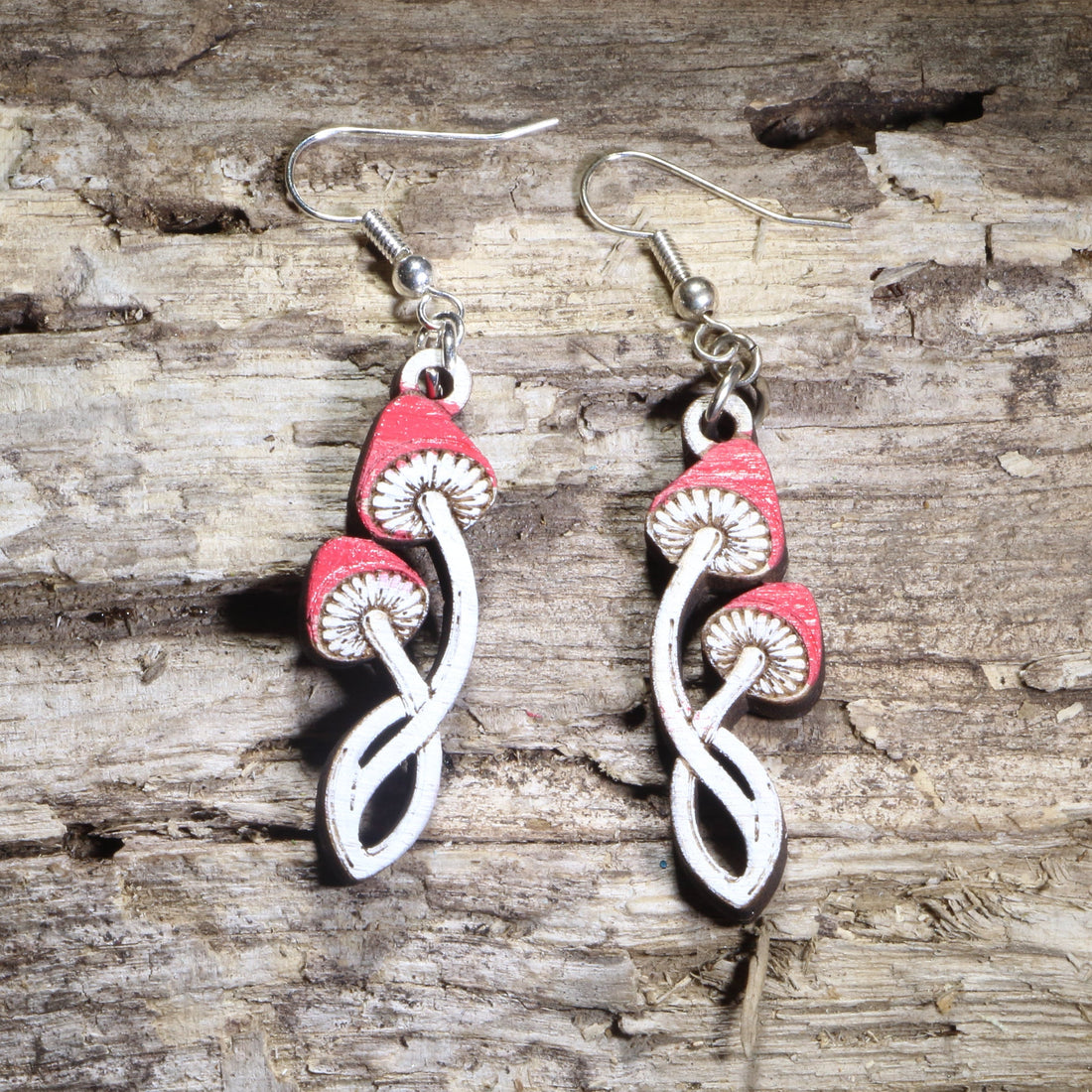 Handcrafted twisted toadstool mushroom wooden dangle earrings featuring whimsical red-and-white toadstools with curved stems and hand-painted details. Lightweight laser-cut wooden earrings with hypoallergenic .925 sterling silver hooks, perfect for cottagecore fashion, mushroom lovers, forest enthusiasts, fairycore style, fantasy fans, and nature-inspired handmade jewelry.