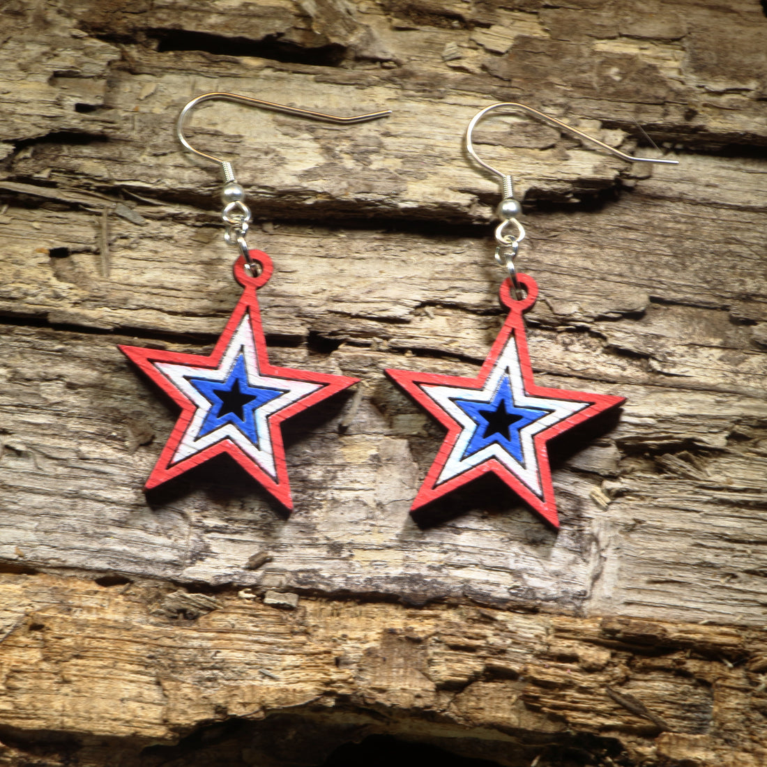 Hand-painted wooden patriotic star dangle earrings featuring layered red, white, and blue star design, hypoallergenic sterling silver hooks, and lightweight Americana jewelry for Fourth of July celebrations, veterans, and patriotic everyday style by Cate’s Concepts.