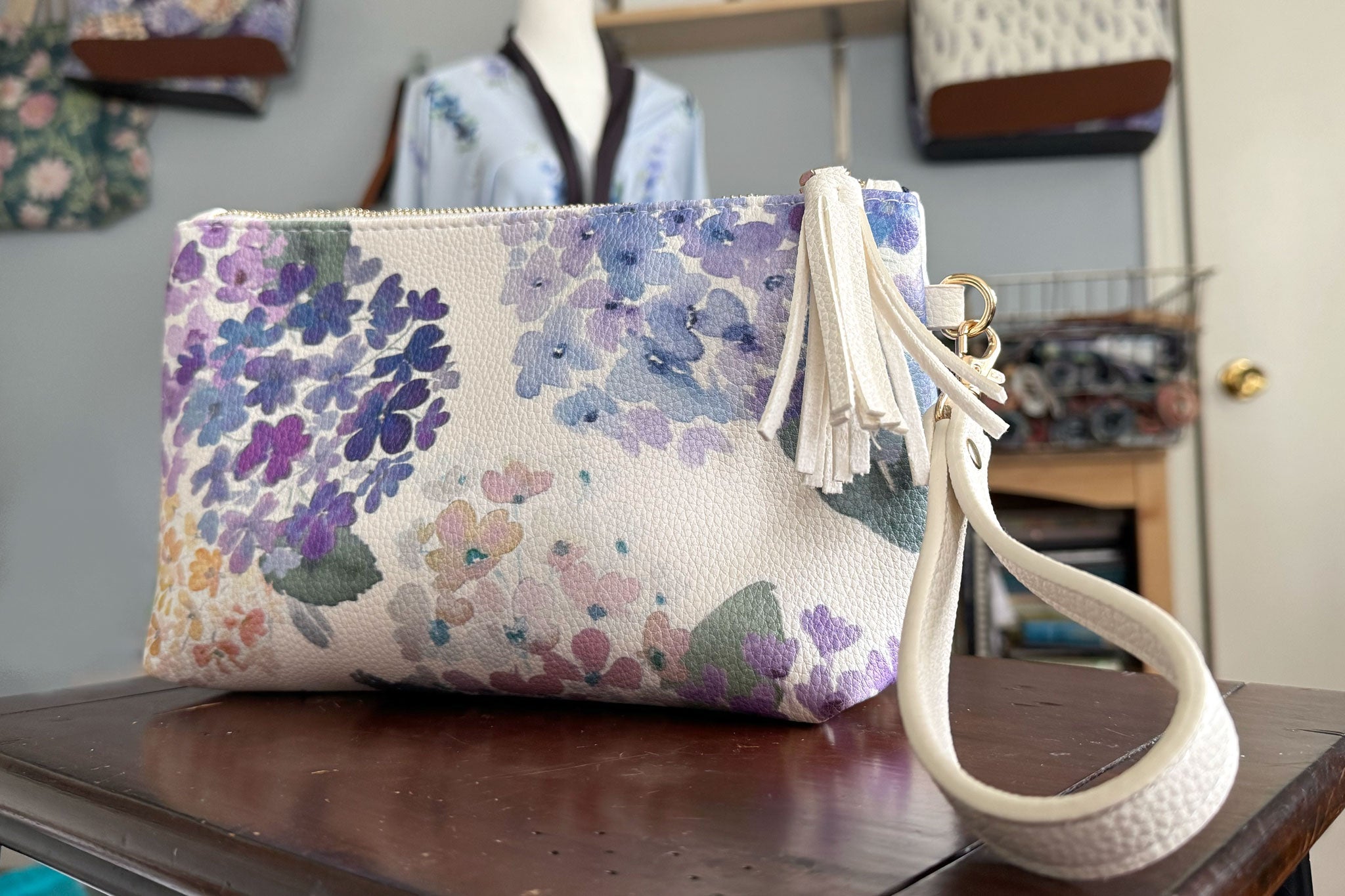 Floral-patterned pouch with a white strap on a wooden surface