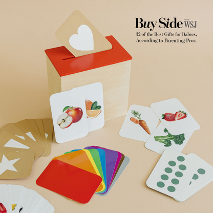 Wooden box and colorful educational flashcards with images of fruits, vegetables, and shapes on a beige background.