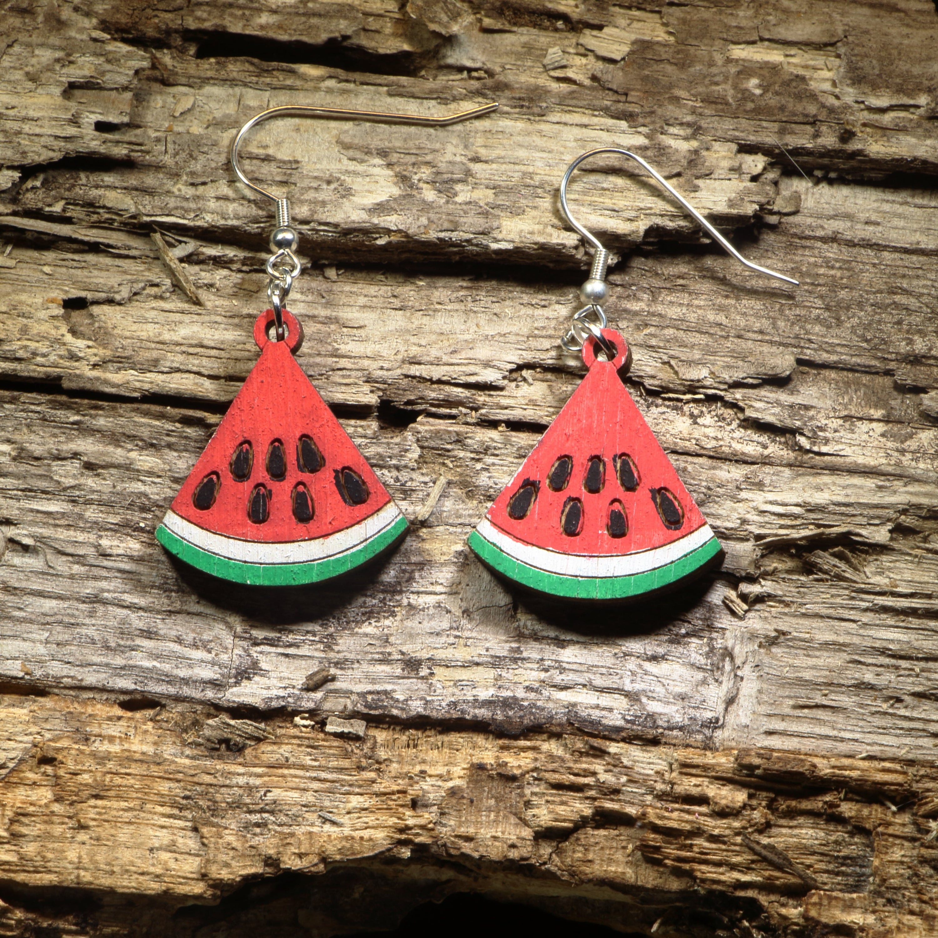 Hand-painted wooden watermelon slice dangle earrings featuring juicy watermelon wedges with vibrant red, green, and black seed details. Crafted from lightweight wood with hypoallergenic .925 sterling silver hooks, these cheerful earrings are perfect for summer fashion, fruit lovers, farmers markets, picnics, beach vacations, and anyone who enjoys playful food-inspired jewelry.