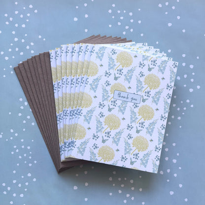 Fanned stack of eight thank you greeting cards with yellow &amp; blue floral print, and kraft brown envelopes