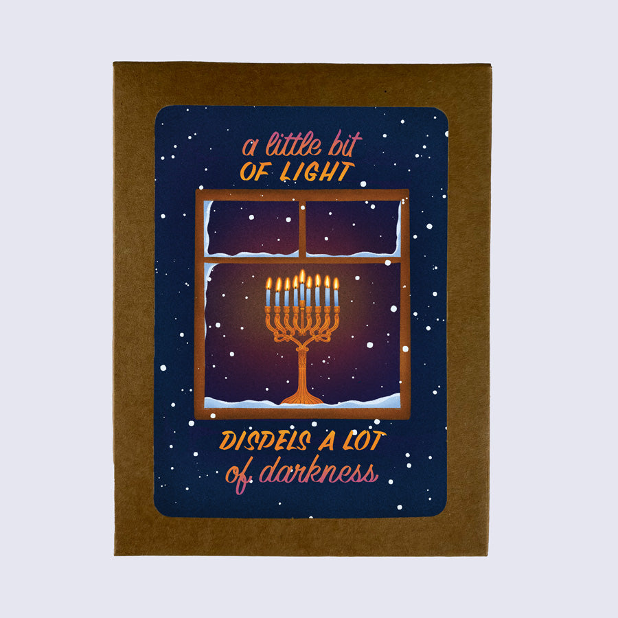 A greeting card with a Hanukkah theme, showing a window with lit candles and snowflakes, with the text &