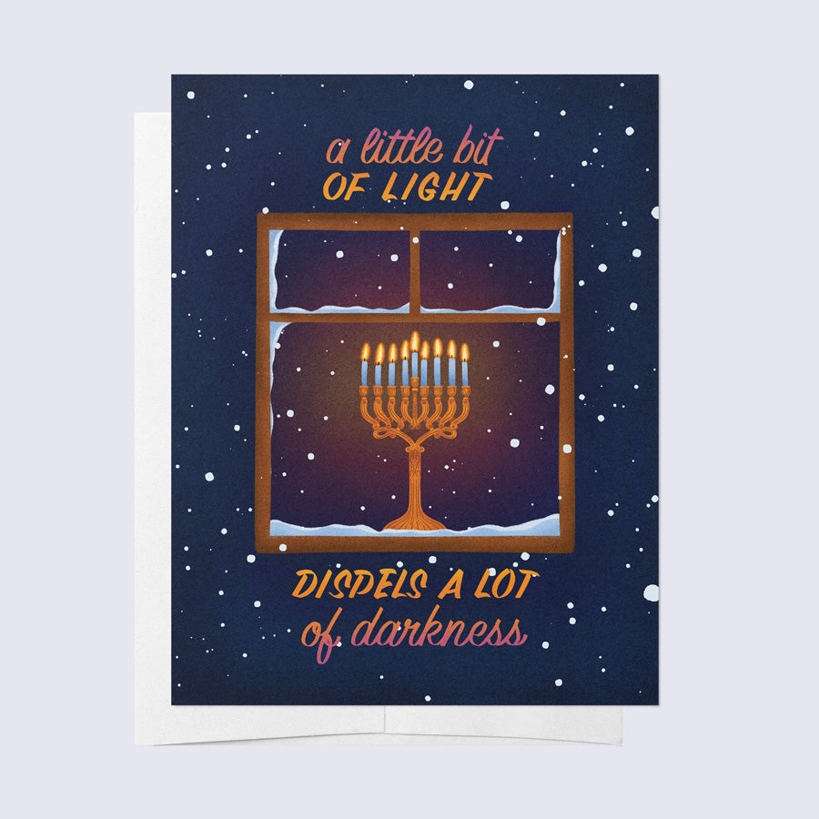 A greeting card with a Hanukkah theme, showing a window with a lit candle and snowflakes outside, with a title &