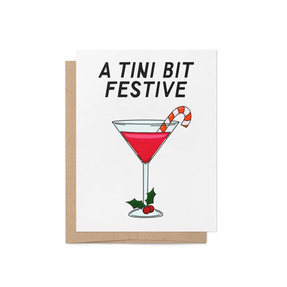 Illustrated holiday greeting card with a red martini, candy cane garnish, and holly, featuring the phrase "A Tini Bit Festive" in bold lettering.