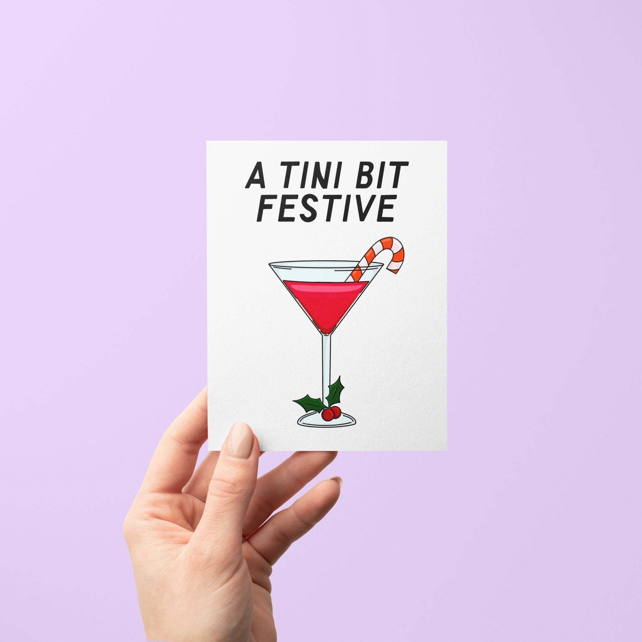 Illustrated holiday greeting card with a red martini, candy cane garnish, and holly, featuring the phrase "A Tini Bit Festive" in bold lettering.