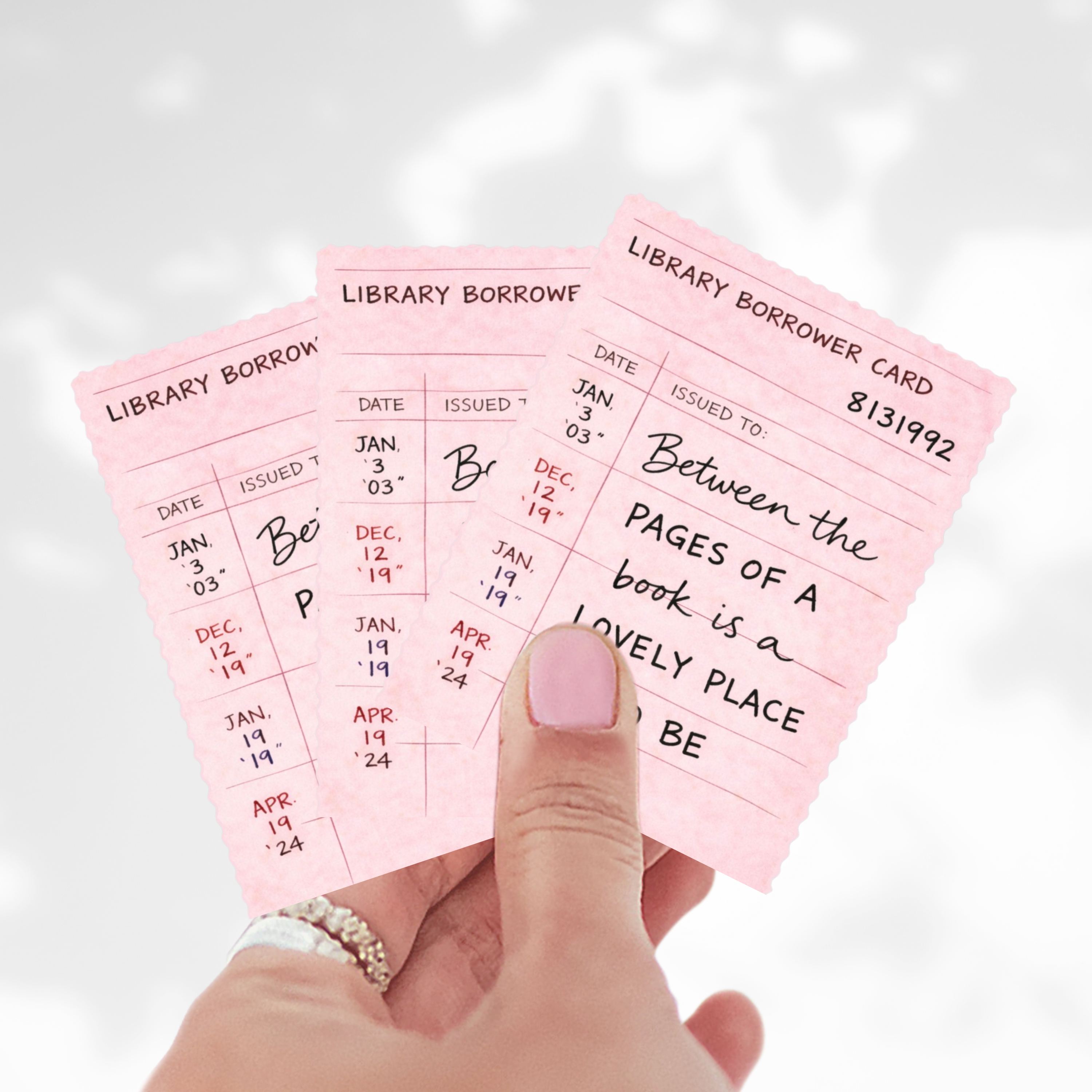 Pink library borrower card stickers held by a hand with a white background