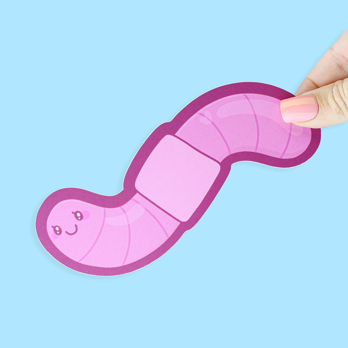 Pink toy worm held by a hand against a light blue background