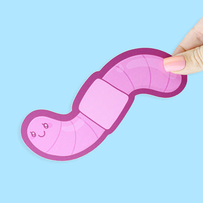 Pink toy worm held by a hand against a light blue background