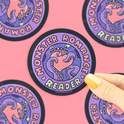 A circular sticker with a purple and pink monster illustration and the words &