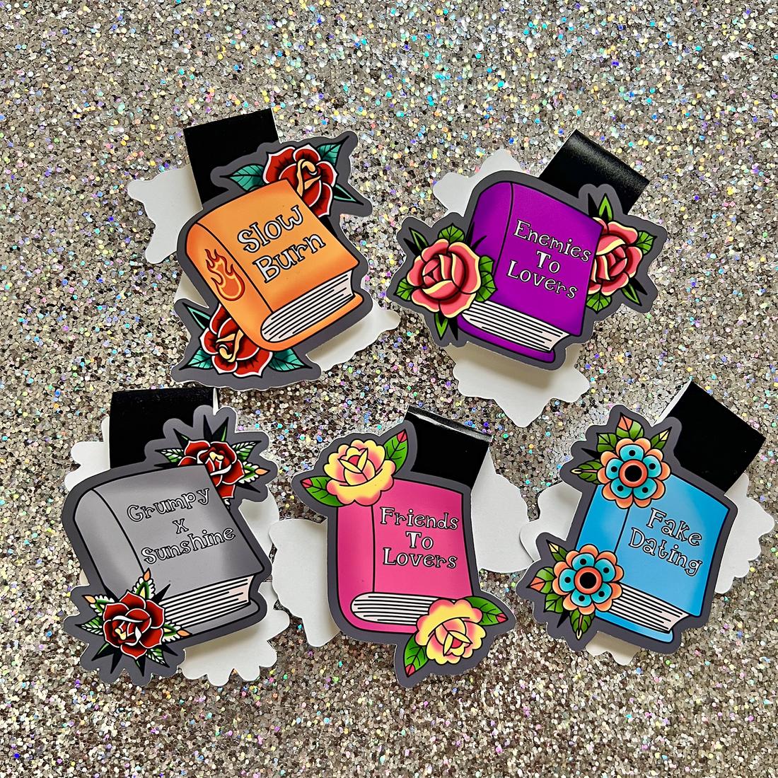 Colorful book-shaped pins with romantic text on a glittery background