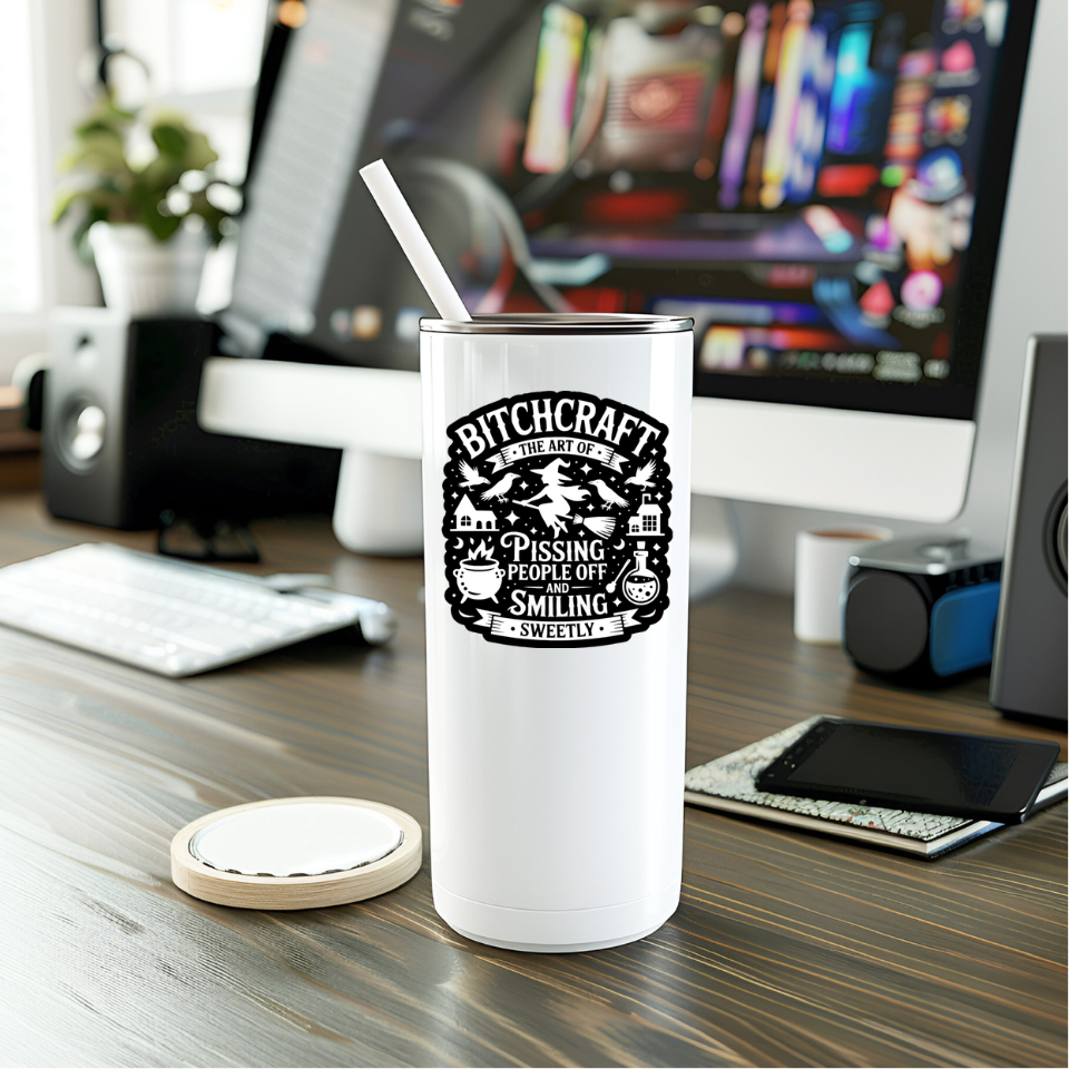 White tumbler with a humorous design on a desk with computer equipment.