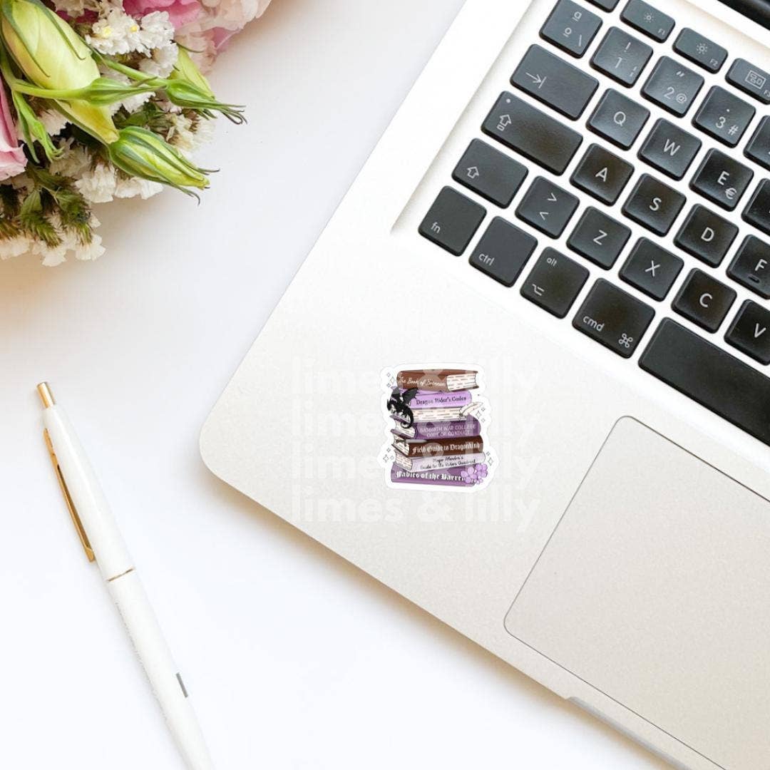 Laptop with a decorative sticker on a white surface with flowers and a pen.