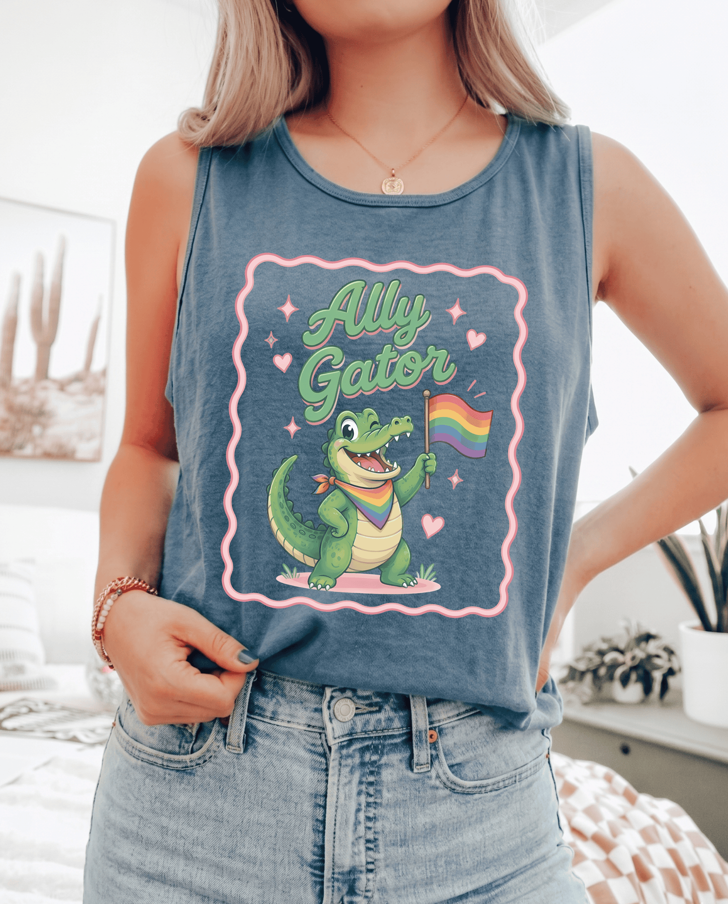 Person wearing a tank top with a cartoon gator holding a rainbow flag and &