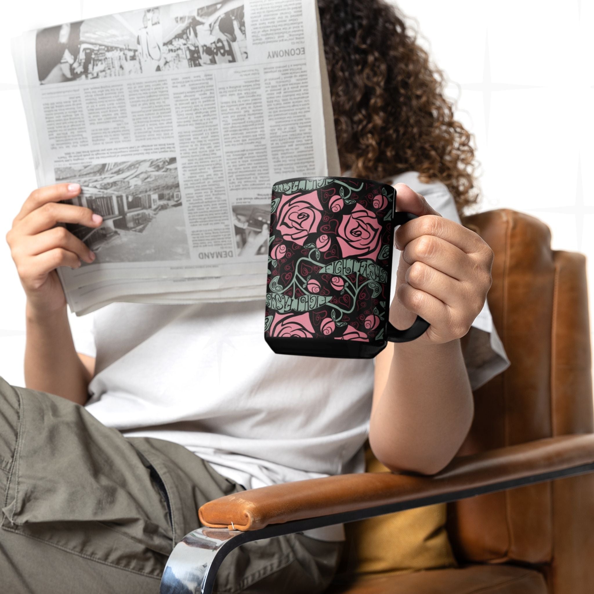 Person reading a newspaper holding the Fight Fascism anti-fascist coffee mug, warm pink rose pattern on black ceramic