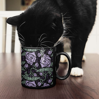 Black cat inspecting anti-Trump hidden message mug with lavender rose botanical wrap print on wooden surface