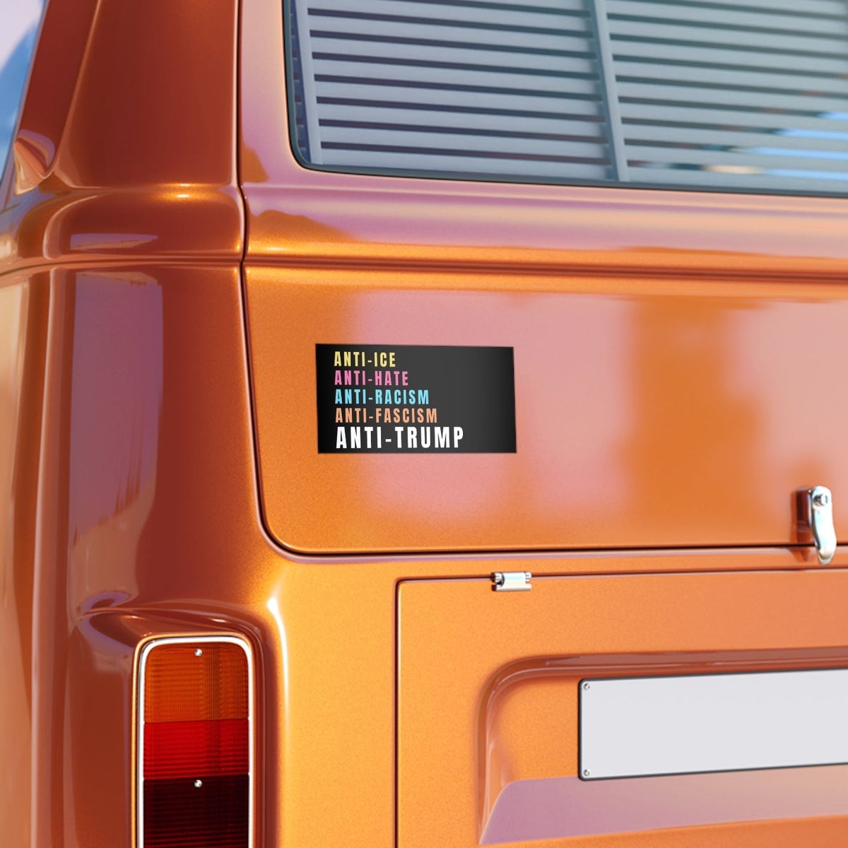 Close-up of an orange vehicle with a bumper sticker on back reading "anti-ice, anti-hate, anti-racism, anti-fascism, anti-trump"