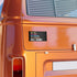 Close-up of an orange vehicle with a bumper sticker on back reading "anti-ice, anti-hate, anti-racism, anti-fascism, anti-trump"