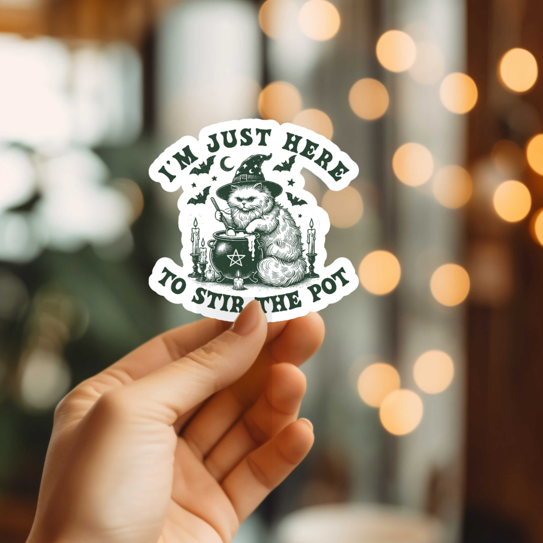 Hand holding a sticker with a festive design against a blurred background with lights