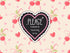 A heart-shaped sticker with a black chalkboard-style center, pink beaded border, and white text reading &