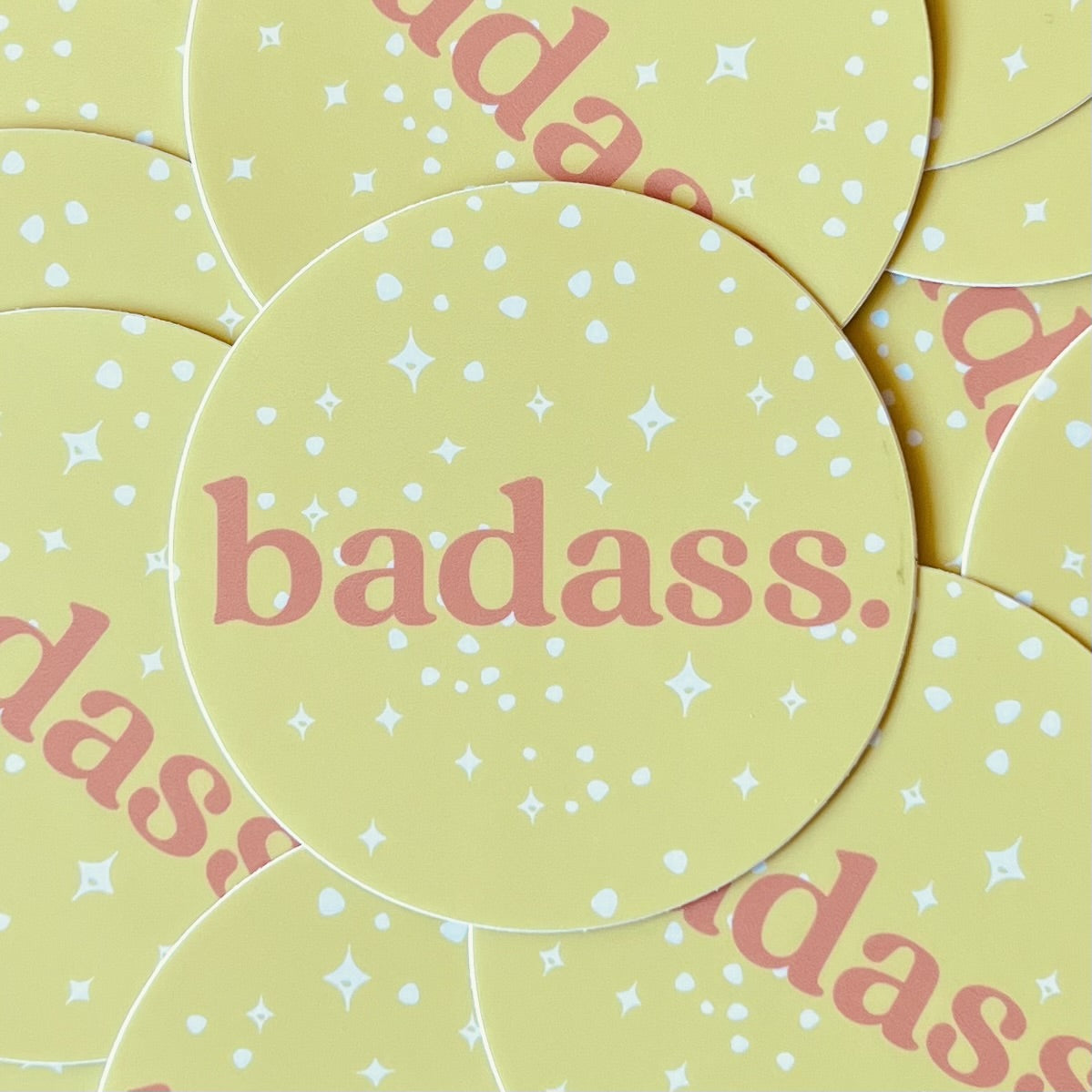Yellow round sticker with white spots &amp; stars and the word badass in dark pink ink