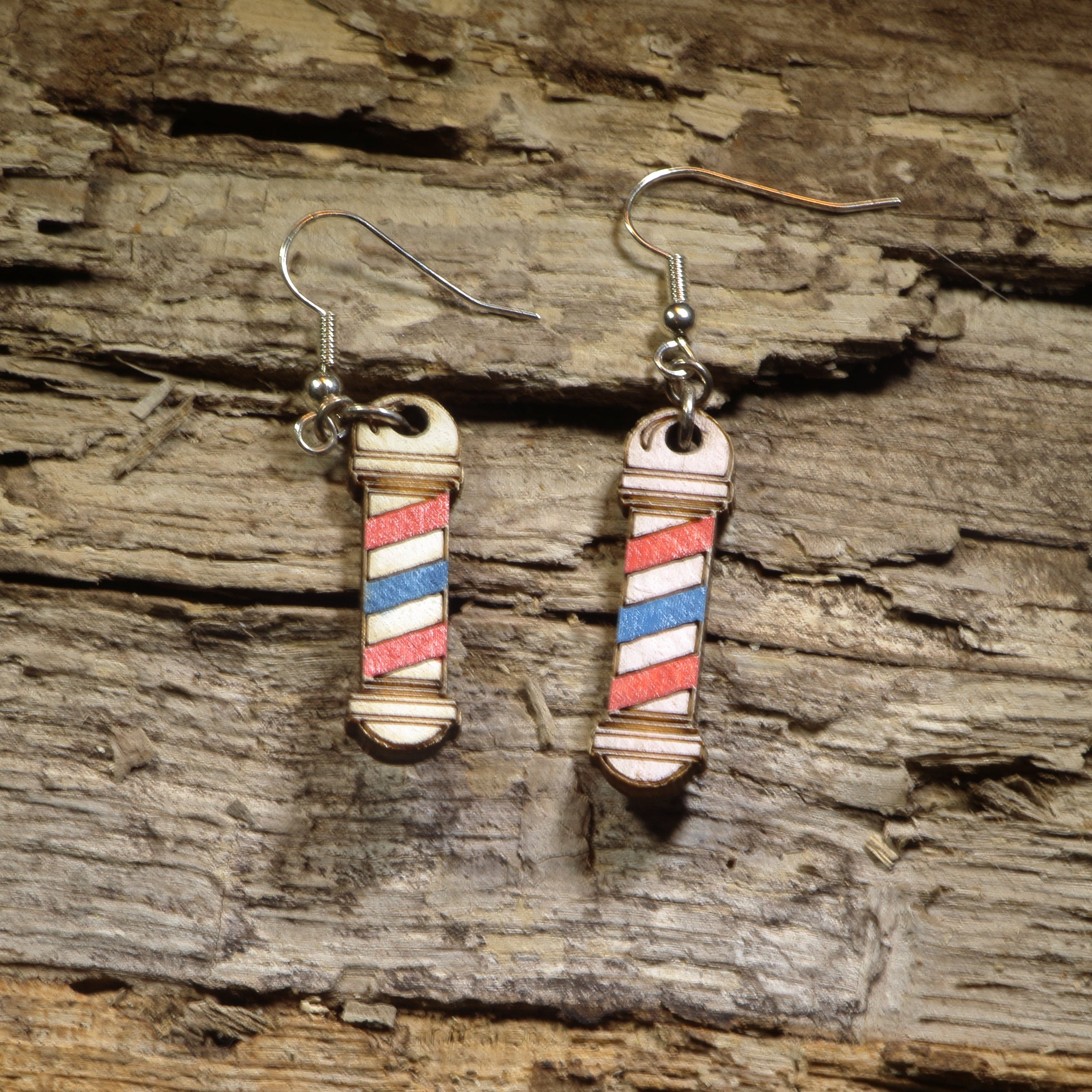 Hand-painted wooden barber pole dangle earrings featuring the iconic red, white, and blue barber pole design. Crafted from lightweight wood with hypoallergenic .925 sterling silver hooks, these fun barber earrings are perfect for barbers, hairstylists, cosmetologists, beauty school students, salon owners, and anyone who loves unique profession-inspired jewelry.