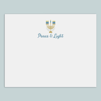 A white envelope with a graphic design featuring a menorah and the text "Peace &amp; Light" printed on it.
