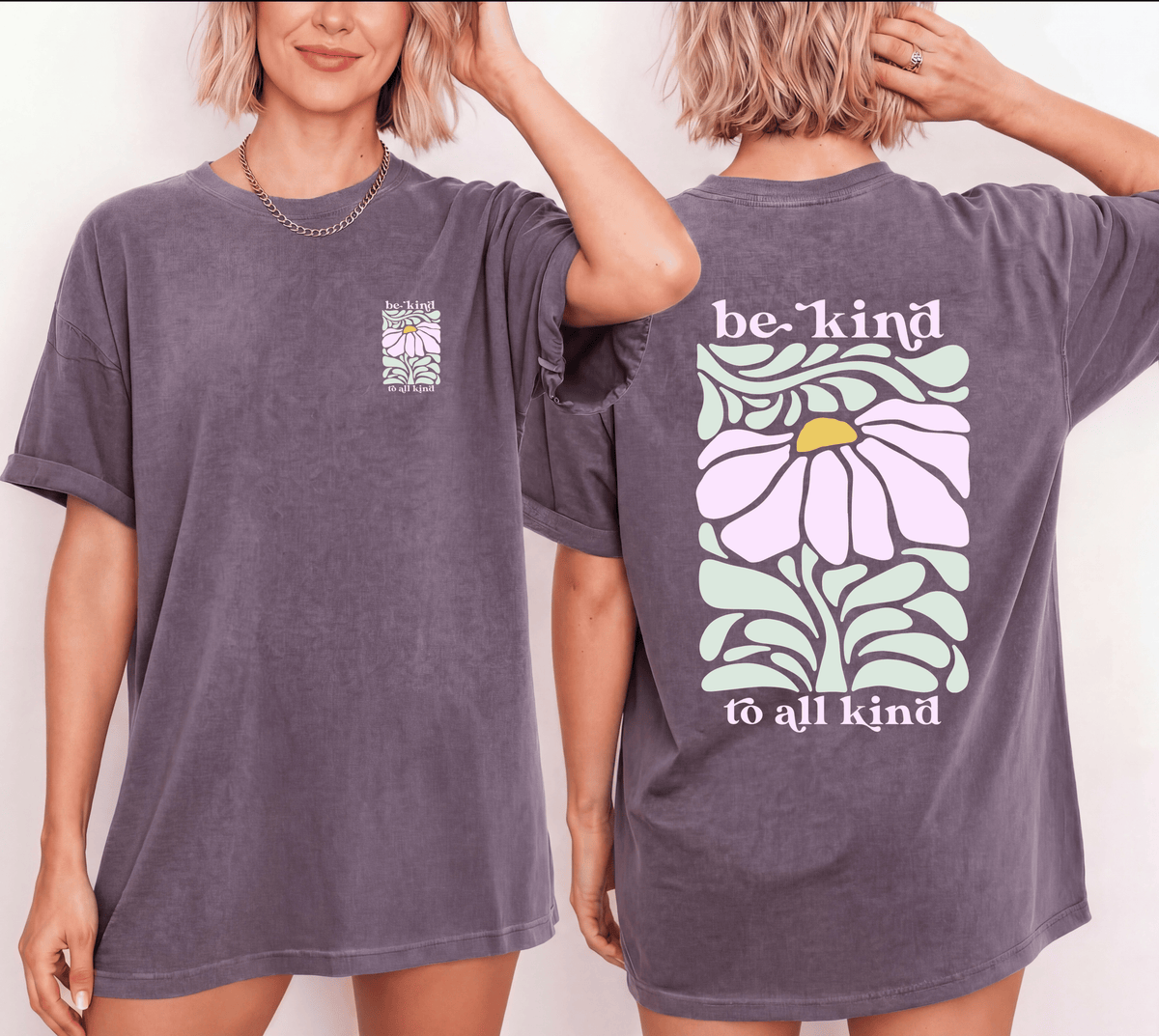 Front and back views of a muted purple Be Kind to All Kind T-shirt with a pastel pink flower, mint-green leaves, and coordinating chest and back prints.